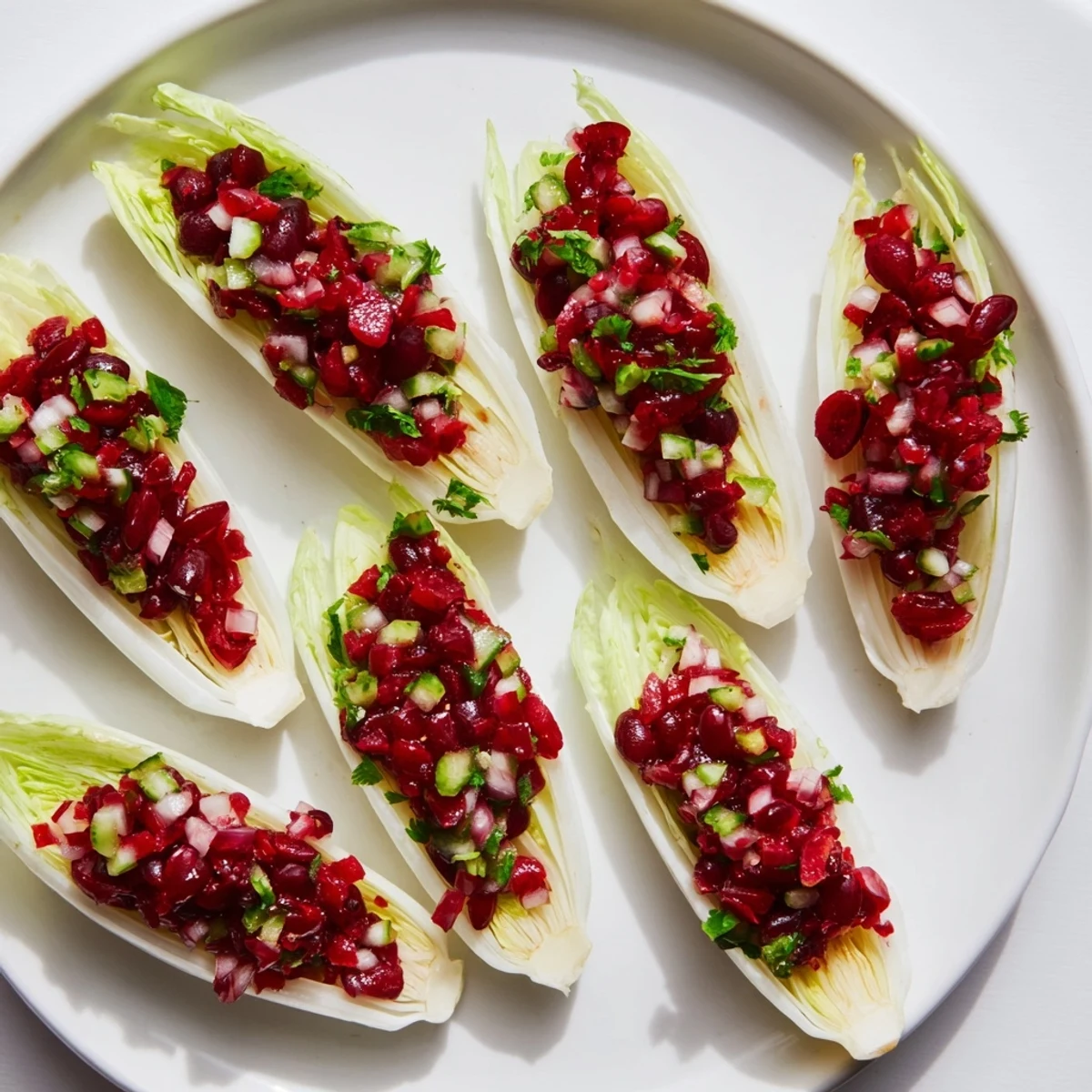 Colorful cranberry jalapeño salsa nestled in endive, perfect for holiday gatherings.  
