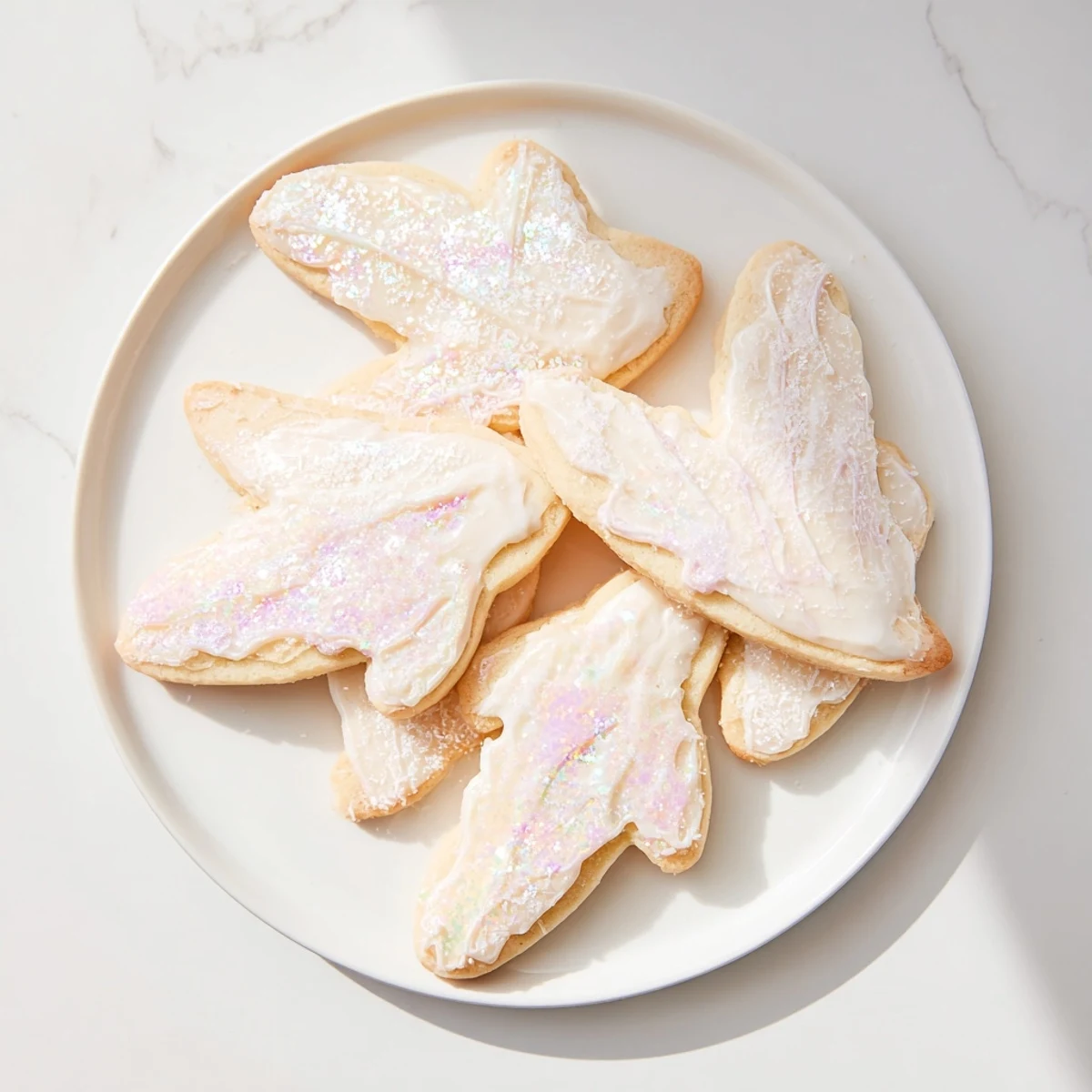 Golden-edged Angel Wings Sugar Cookies arranged on a plate, ready for festive enjoyment.