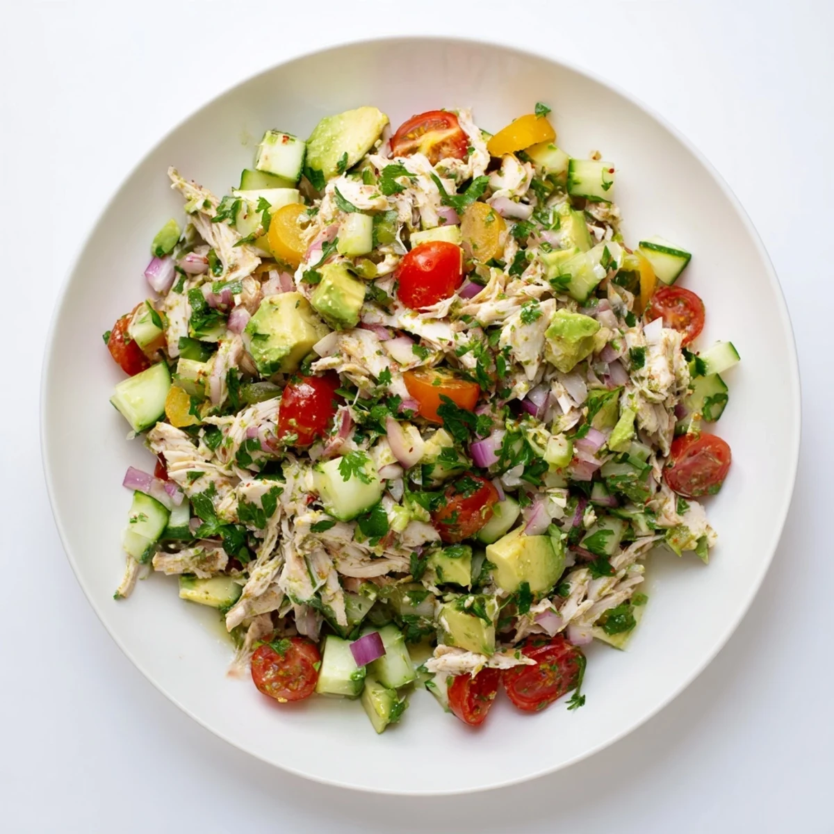 A vibrant serving of avocado chicken salad with diced avocado, cucumber, and red onion on a rustic table.