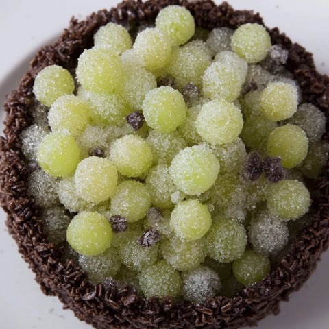 Sparkling sugar-dusted grapes and rock candy gleam within a dark chocolate cracker "Crystal Cave" dessert.