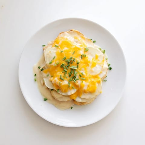 A close-up of a casserole dish filled with the decadent, layered Cheesy Scalloped Potatoes.