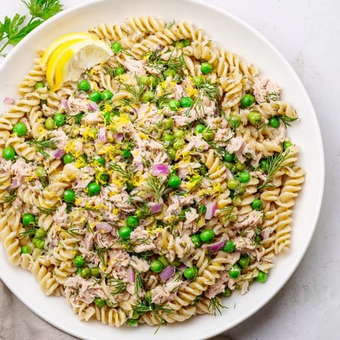 Serve this refreshing Lemony Tuna Pasta Salad for a quick lunch or light dinner, featuring crisp red onion and optional capers for extra flavor.  