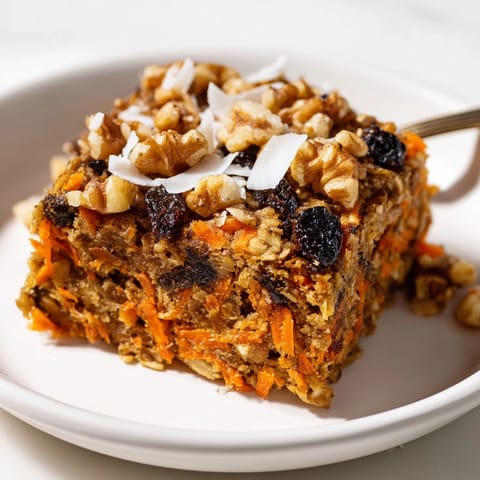 Golden-brown Carrot Cake Baked Oatmeal fresh from the oven, revealing a moist, spiced interior studded with shredded carrots and plump raisins.
