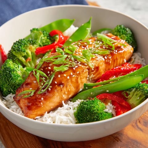 Tender Maple Soy Glazed Salmon resting on a bed of jasmine rice, garnished with sesame seeds and fresh green onions for a delicious weeknight meal.