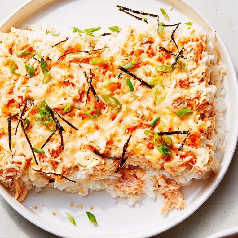 A close-up of a creamy layered Creamy Salmon Sushi Bake, featuring golden cheese and flaky fish.