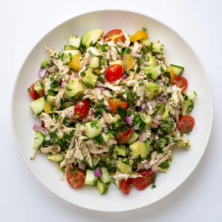 A vibrant serving of avocado chicken salad with diced avocado, cucumber, and red onion on a rustic table.