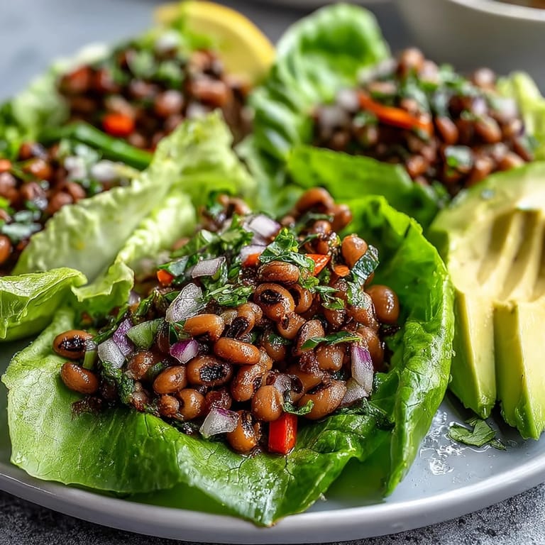 Close-up of vibrant Black-Eyed Pea Lettuce Wraps showcasing red onions, bell peppers, and shredded carrots inside butter lettuce leaves.